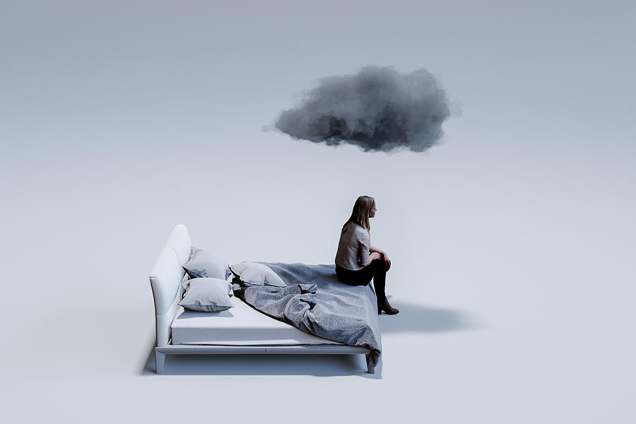 Sad mid adult woman sitting on corner of double bed with dark cloud above head. Photograph by OsakaWayne Studios