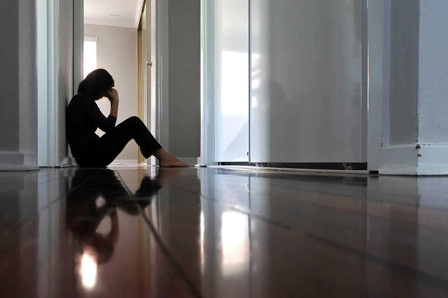 Sad woman sitting on dark home corridor floor. Photograph by Chameleonseye