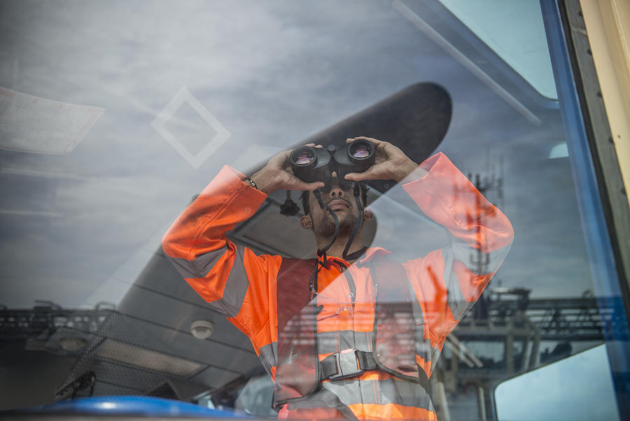 Sailor on tug looking through binoculars Photograph by Monty Rakusen