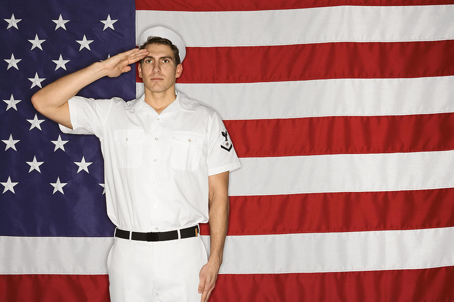 Sailor saluting and American flag Photograph by Jupiterimages