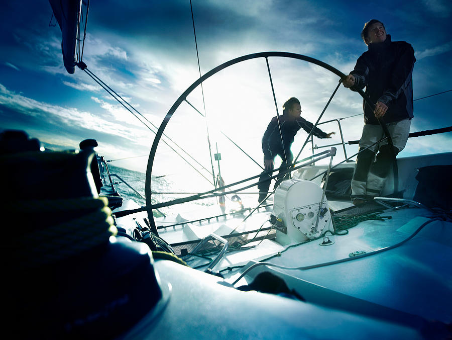 Sailors steering yacht Photograph by Image Source