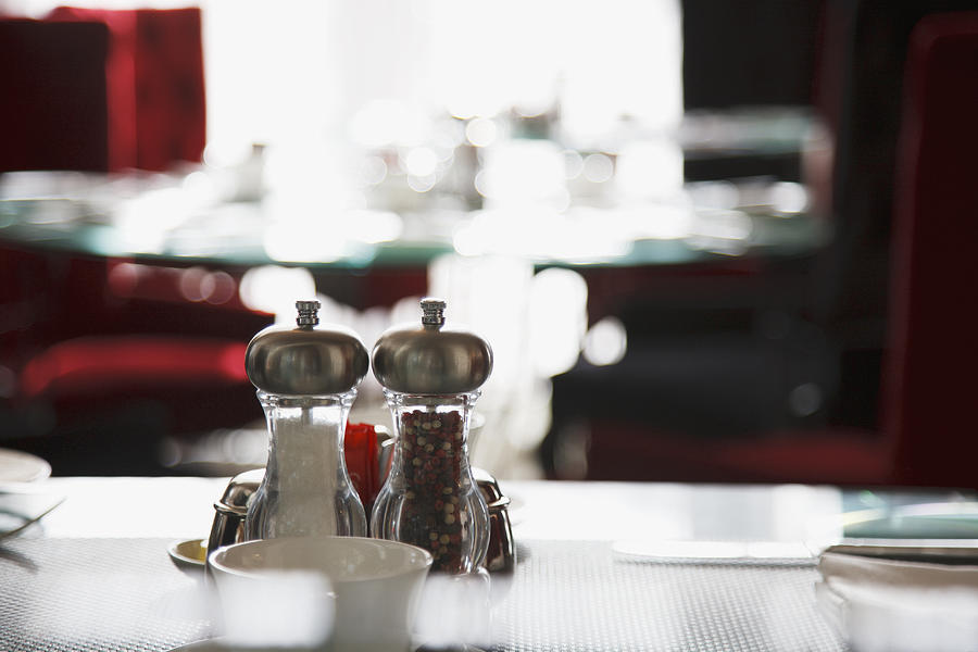 Salt and pepper shakers on restaurant table Photograph by Paul Bradbury