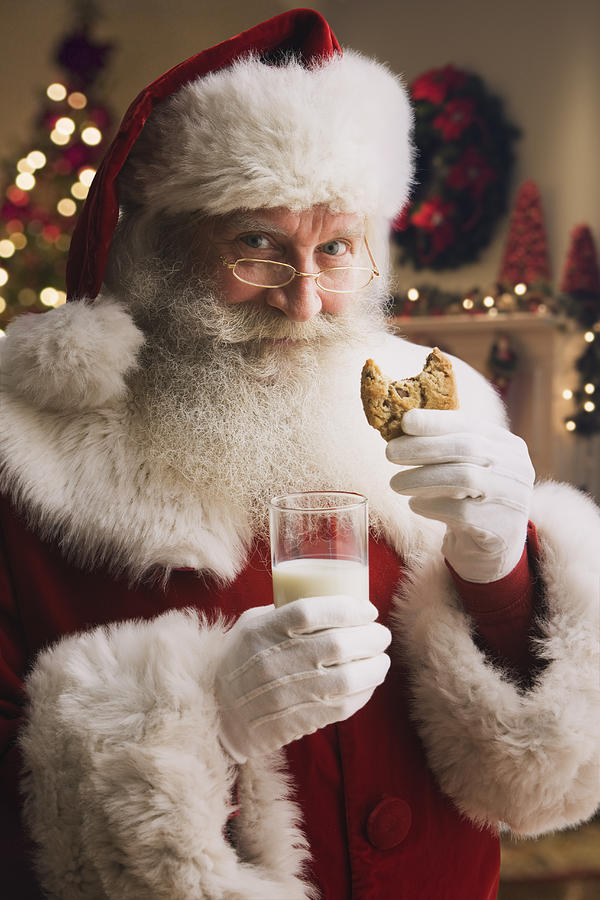 Santa Claus holding biscuit and glass of milk, portrait, close-up Photograph by Jose Luis Pelaez