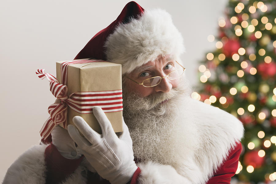 Santa Claus holding gift, smiling, close-up Photograph by Jose Luis Pelaez