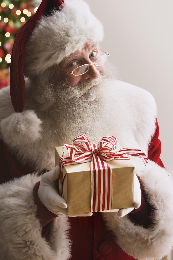 Santa Claus holding gift, smiling, portrait, close-up Photograph by Jose Luis Pelaez