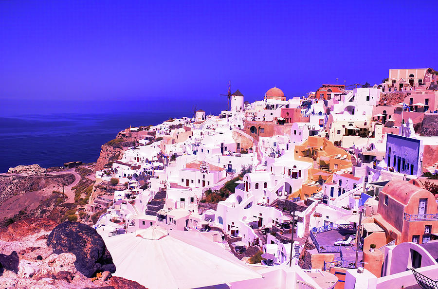 Santorini, Greece Beautiful city of Oia on a hill of white houses with blue  roof and windmills against dramatic pink sky, located in Greek Cyclades