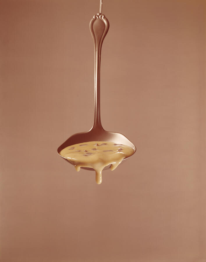 Sauce dripping from ladle against brown background Photograph by Tom Kelley Archive