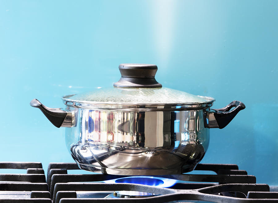 Saucepan boiling on gas stove with steam jet rising Photograph by RapidEye