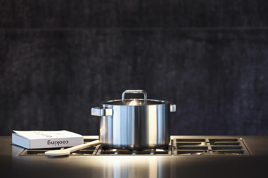 Saucepan, cookery book and wooden spoon on hob. Photograph by Studio Blond