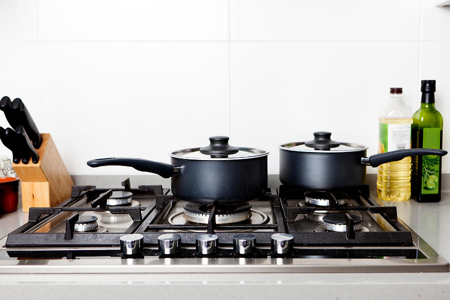 Saucepans on gas hob Photograph by Image Source
