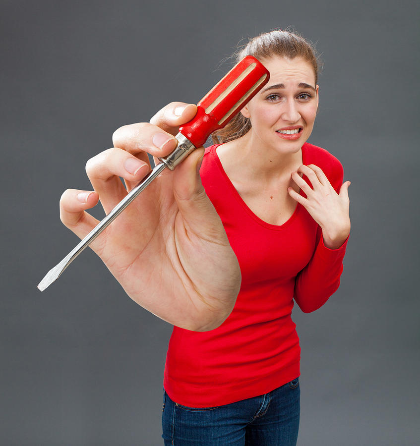 scared beautiful young woman with symbolic screwdriver for DIY fear Photograph by Studio Grand Web