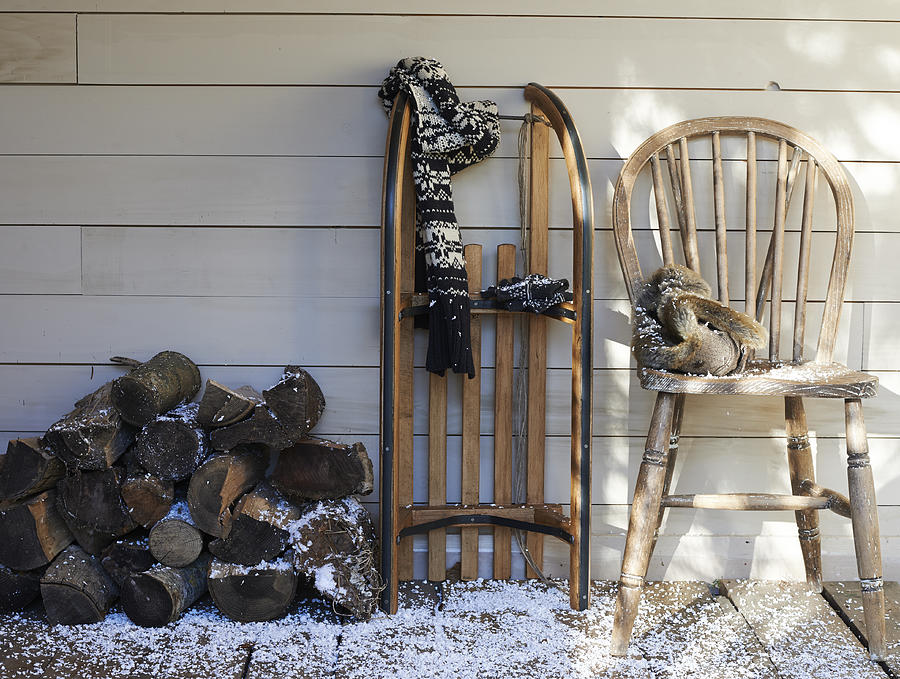 Scarf, wooden sled, chair and firewood on porch Photograph by Paul Viant