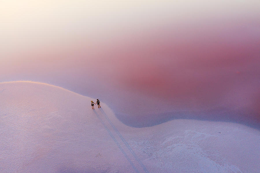 Scenic aerial view of heterosexual walking on  pink salt lake Photograph by Oleh_Slobodeniuk