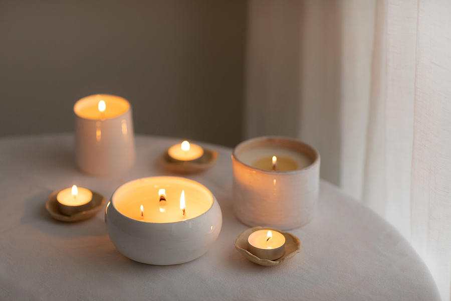 Scented candles in ceramic bowls on linen tablecloth at home. Photograph by Anastasiia Krivenok