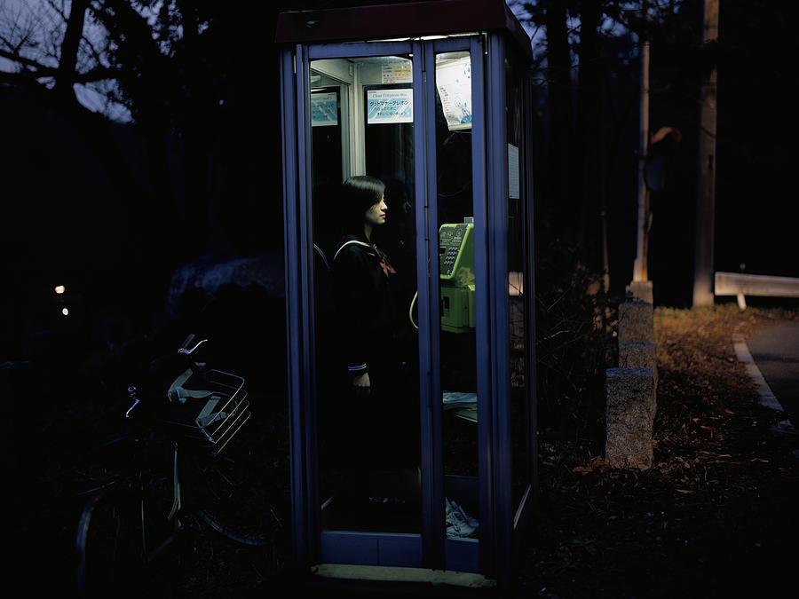 School girl in a public telephone booth Photograph by Dex Image