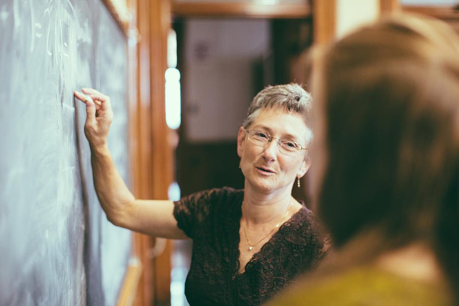 School teacher at chalkboard explaining math teenage student Photograph by Mlenny