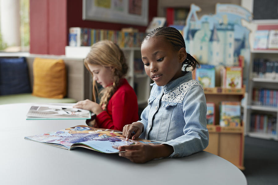 Schoolgirls reading books in school library Photograph by Klaus Vedfelt