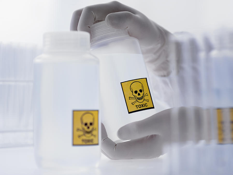 Scientist holding bottle with toxic label Photograph by Adam Gault