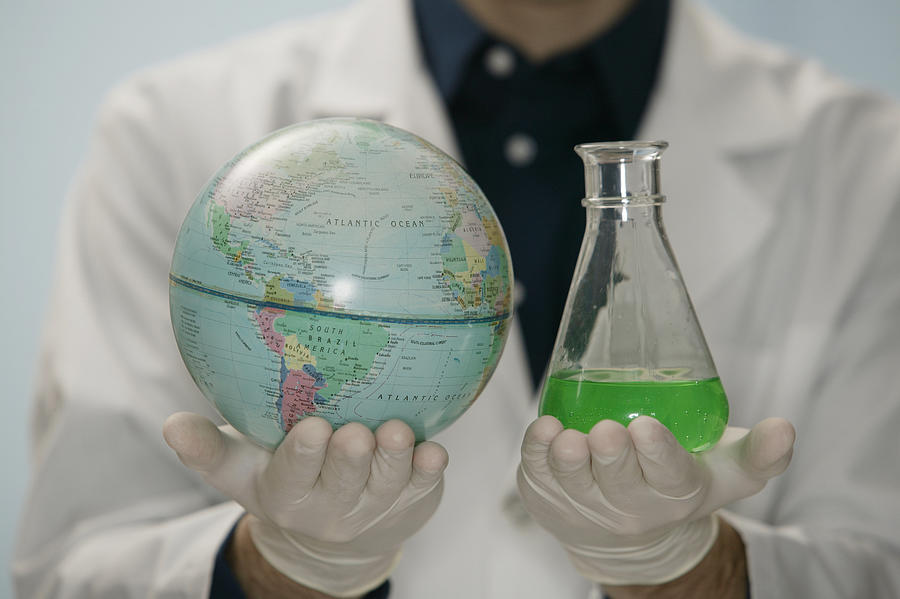 Scientist holding globe and beaker Photograph by Comstock Images