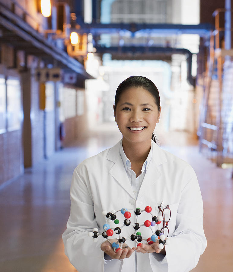 Scientist in factory holding molecule model Photograph by Martin Barraud