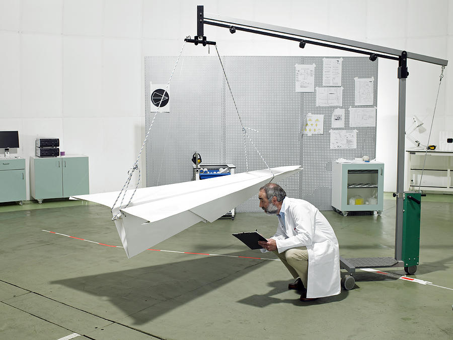 Scientist inspecting paper plane in laboratory Photograph by Michael Blann