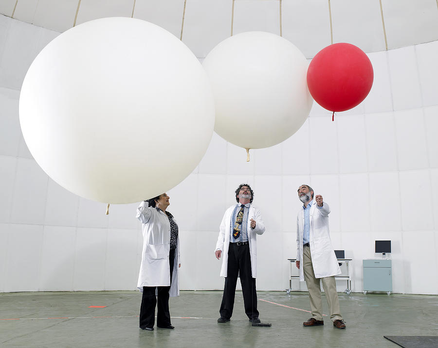 Scientist look upwards at balloons Photograph by Michael Blann