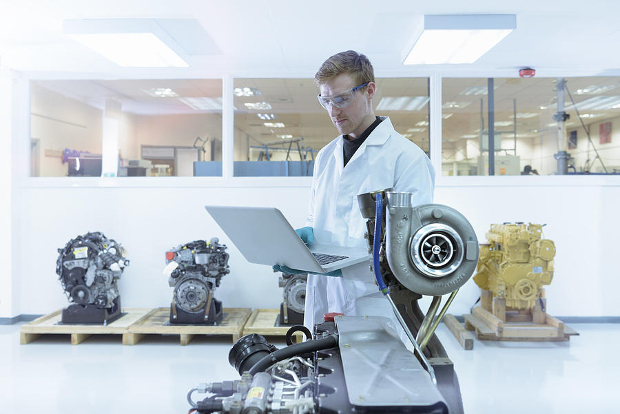 Scientist using laptop in turbo charger automotive research laboratory Photograph by Monty Rakusen