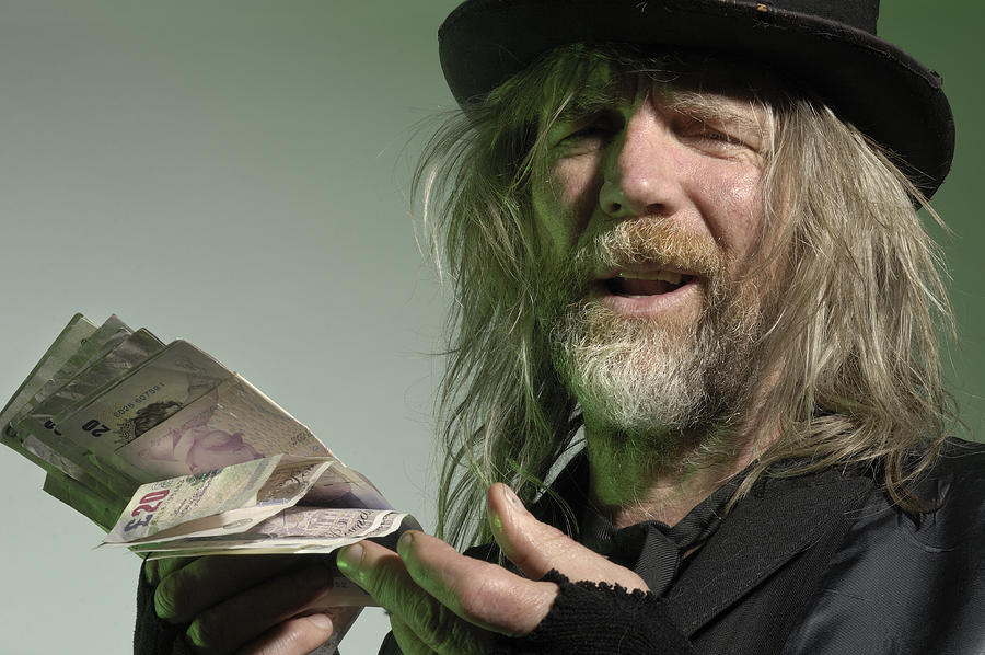 Scruffy mature man holding British pound notes Photograph by Jac Depczyk