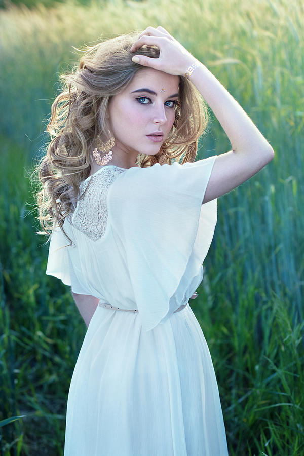 Seductive blonde girl with blue eyes standing in white dress in tall grass Photograph by Nina Sinitskaya