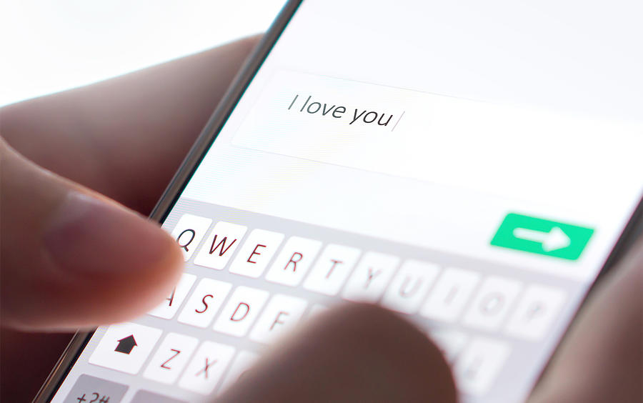Sending I love you text message with mobile phone. Online dating, texting or catfishing concept. Romance fraud, scam or deceit with smartphone. Man writing comment. Photograph by Tero Vesalainen