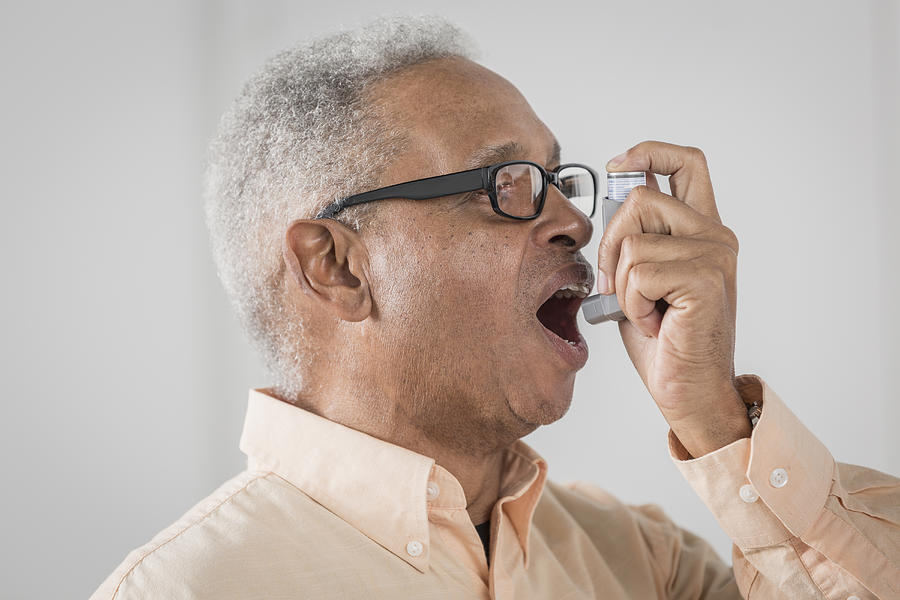 Senior African American man using asthma inhaler Photograph by Terry Vine