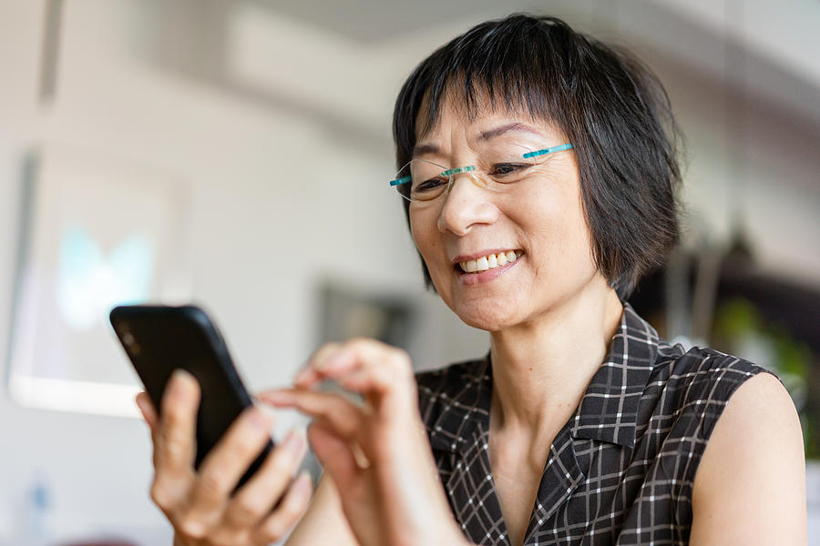 Senior Asian woman using a smartphone Photograph by Yongyuan