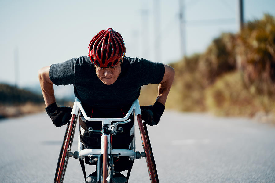 Senior athlete in a racing wheelchair practicing on a rural road. Photograph by Trevor Williams