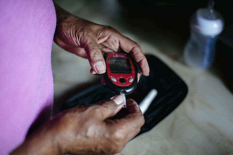 Senior black woman using a diabetes home test kitn Photograph by Willie B. Thomas