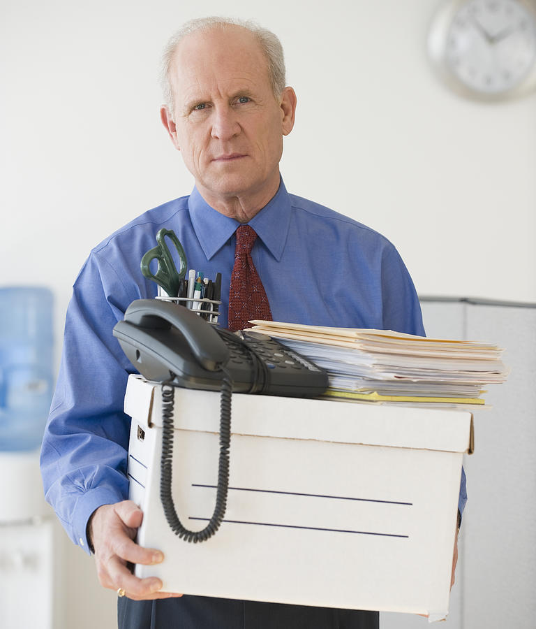 Senior businessman carrying box of office items Photograph by Tetra Images
