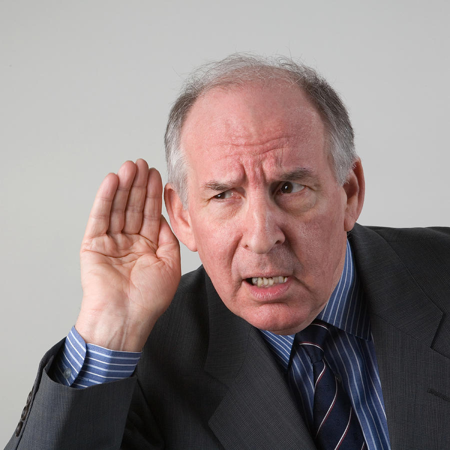 Senior businessman listening with hand cupped to ear, close-up Photograph by GSO Images