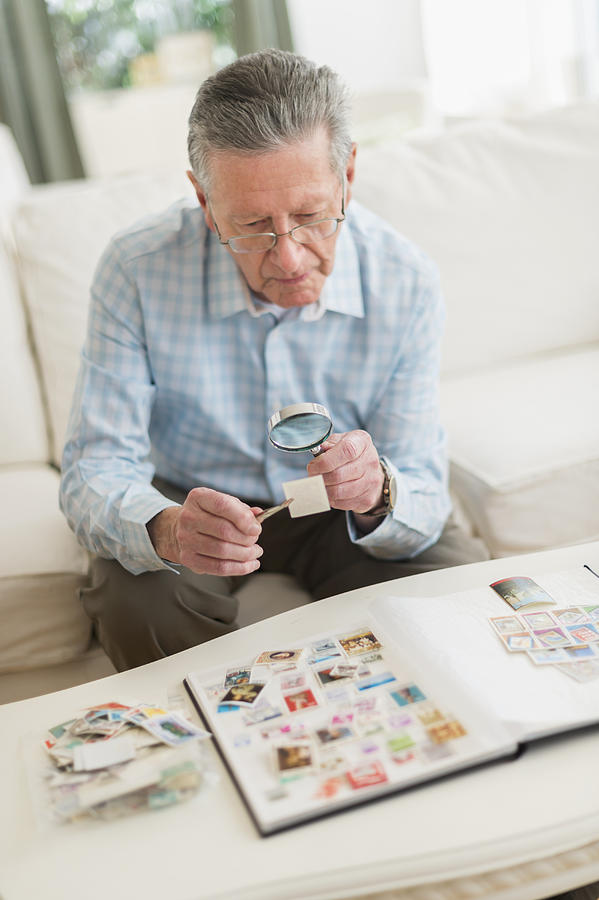 Senior Caucasian man examining stamp collection Photograph by JGI/Tom Grill