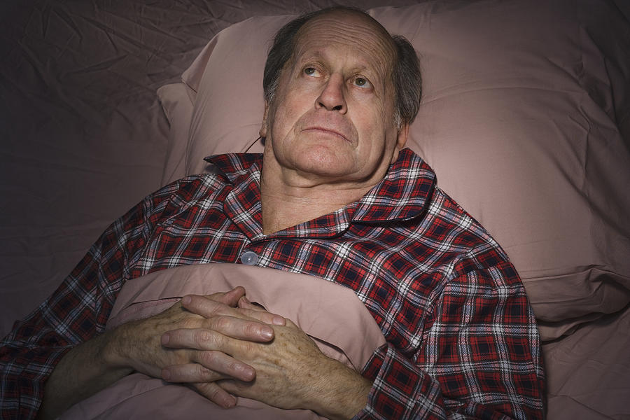 Senior Caucasian man having trouble sleeping Photograph by Steve Prezant