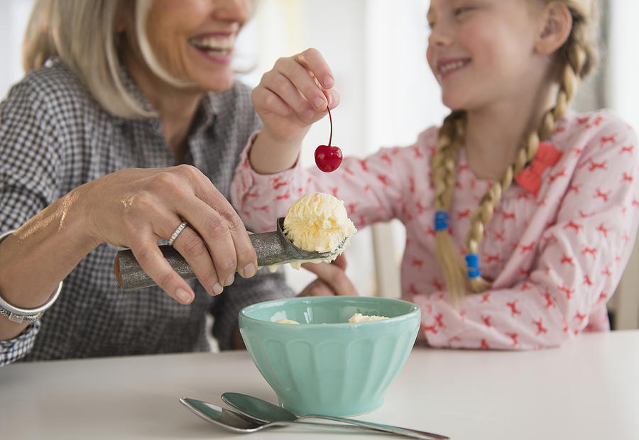 Senior Caucasian woman and granddaughter making ice cream sundae Photograph by JGI/Jamie Grill