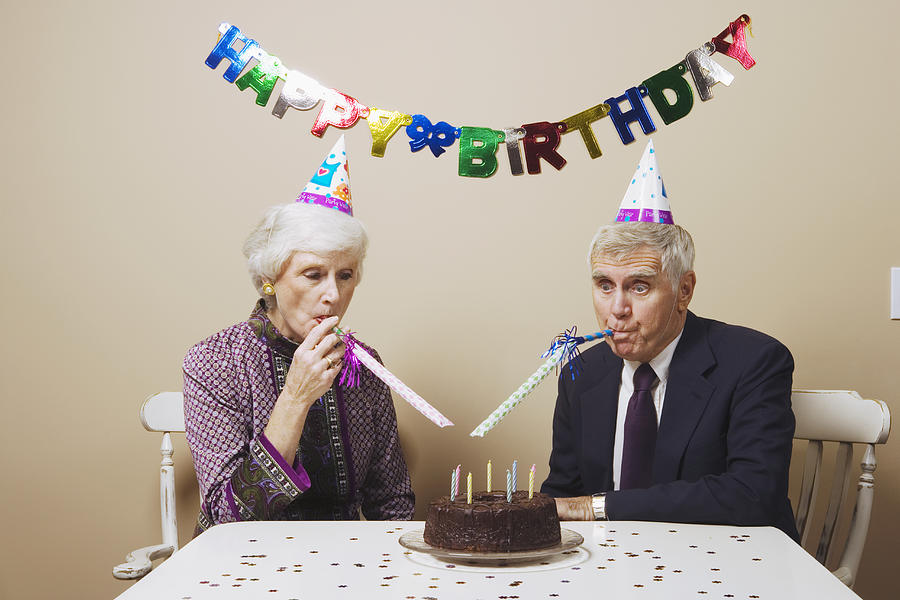 Senior couple celebrating birthday at dining room table Photograph by Paul Burns