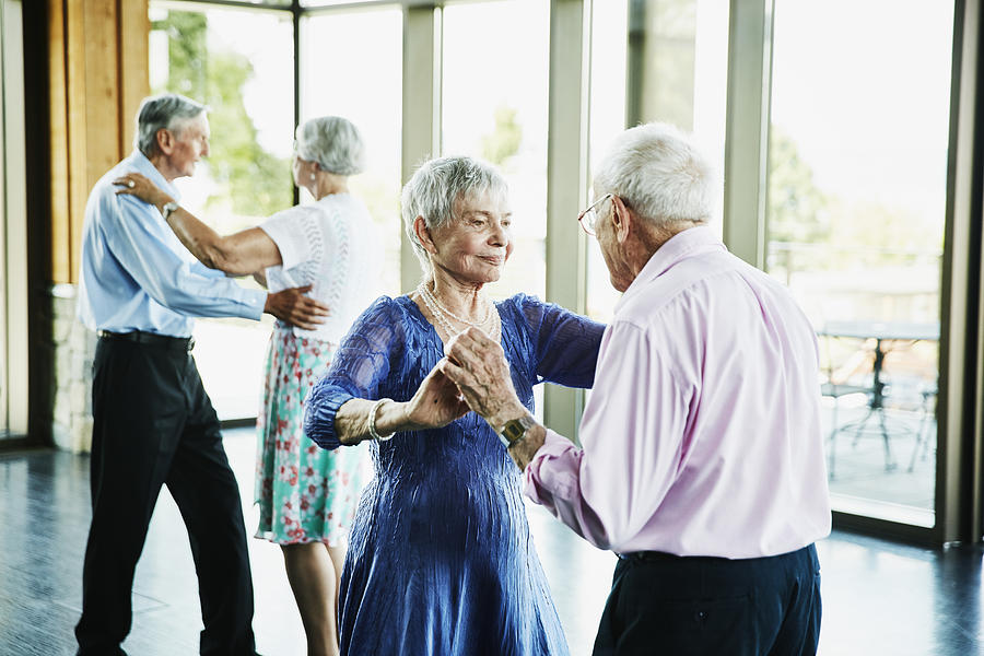 Senior couple dancing together in community center Photograph by Thomas Barwick