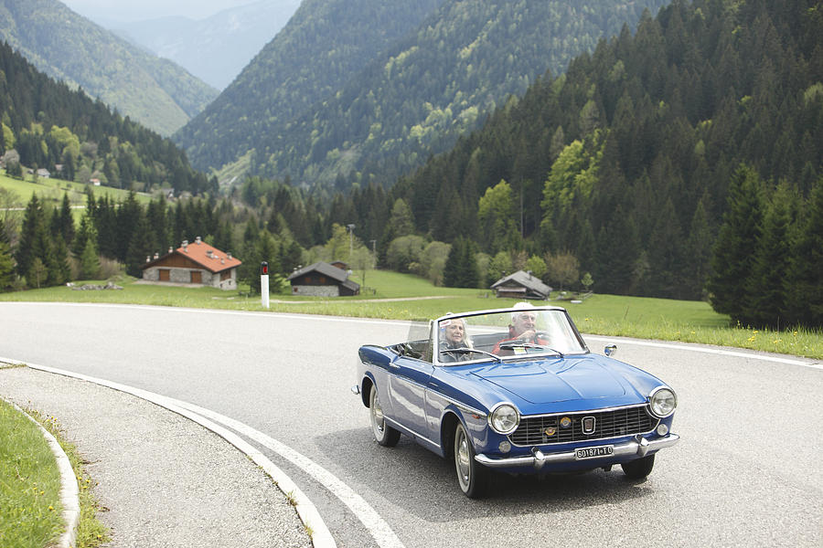 Senior couple driving convertible on country road, Italy Photograph by Andreas Zierhut