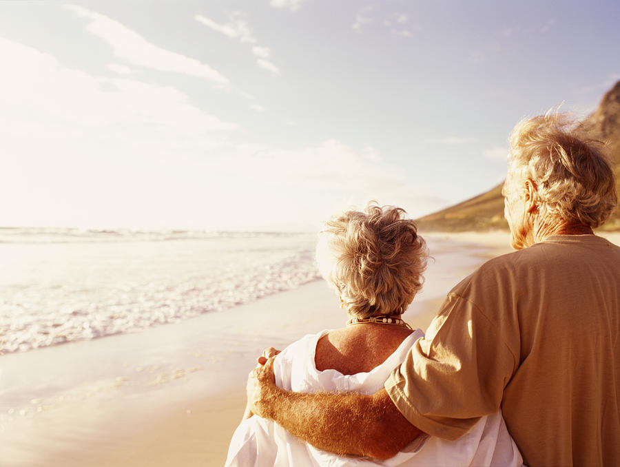 Senior couple embracing on beach, rear view Photograph by Digital Vision