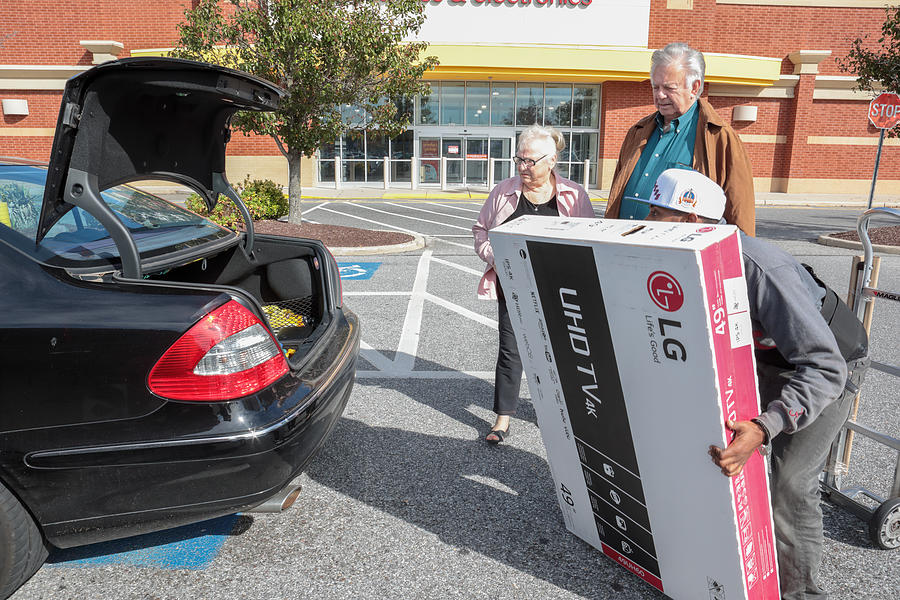 Senior couple gets help at store loading television into car Photograph by Jodi Jacobson