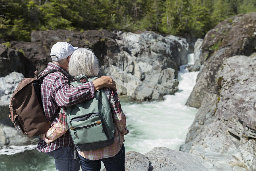 Senior couple hiking in mountains looking at river view Photograph by Compassionate Eye Foundation/Steven Errico