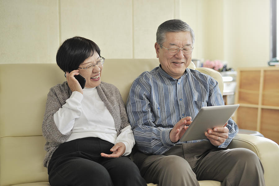 Senior couple is using digital gadgets Photograph by Yagi Studio