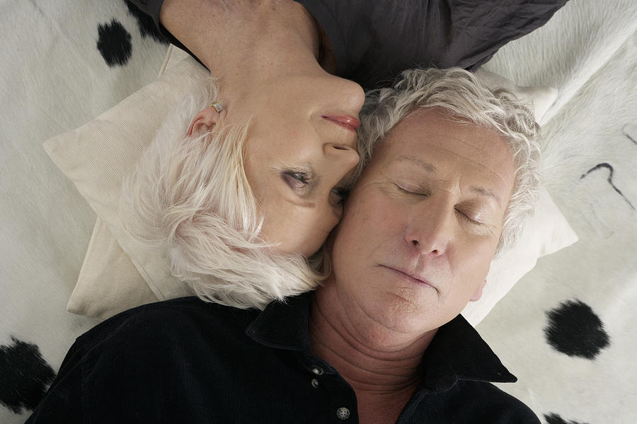Senior couple lying head to head on a cowskin Photograph by Stock4b-rf