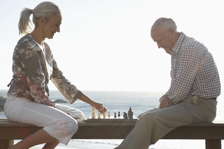 Senior Couple Playing a Game of Chess by the Sea Photograph by Digital Vision.