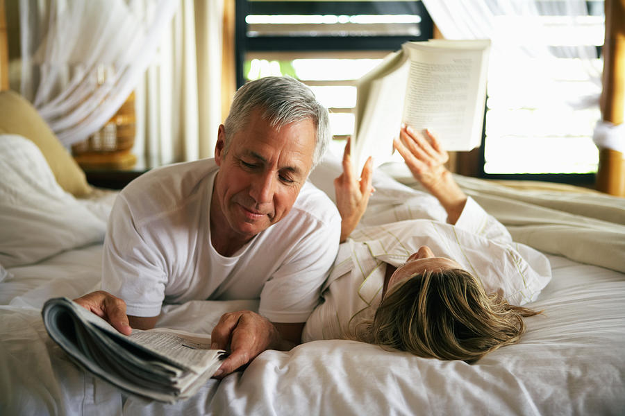 Senior couple reading in bed, close-up Photograph by Kraig Scarbinsky