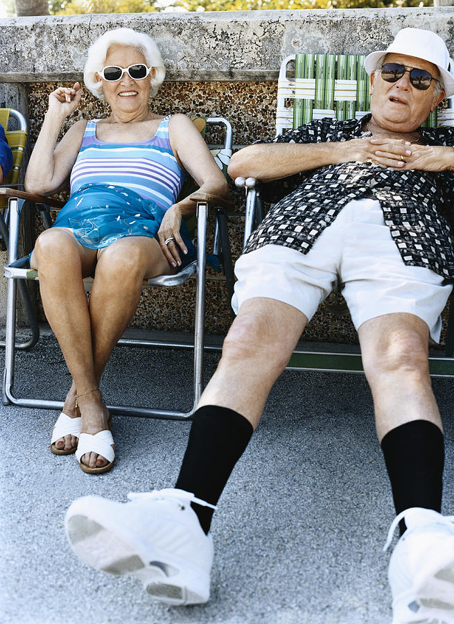 Senior Couple Sit on Chairs Sunbathing Photograph by Digital Vision.
